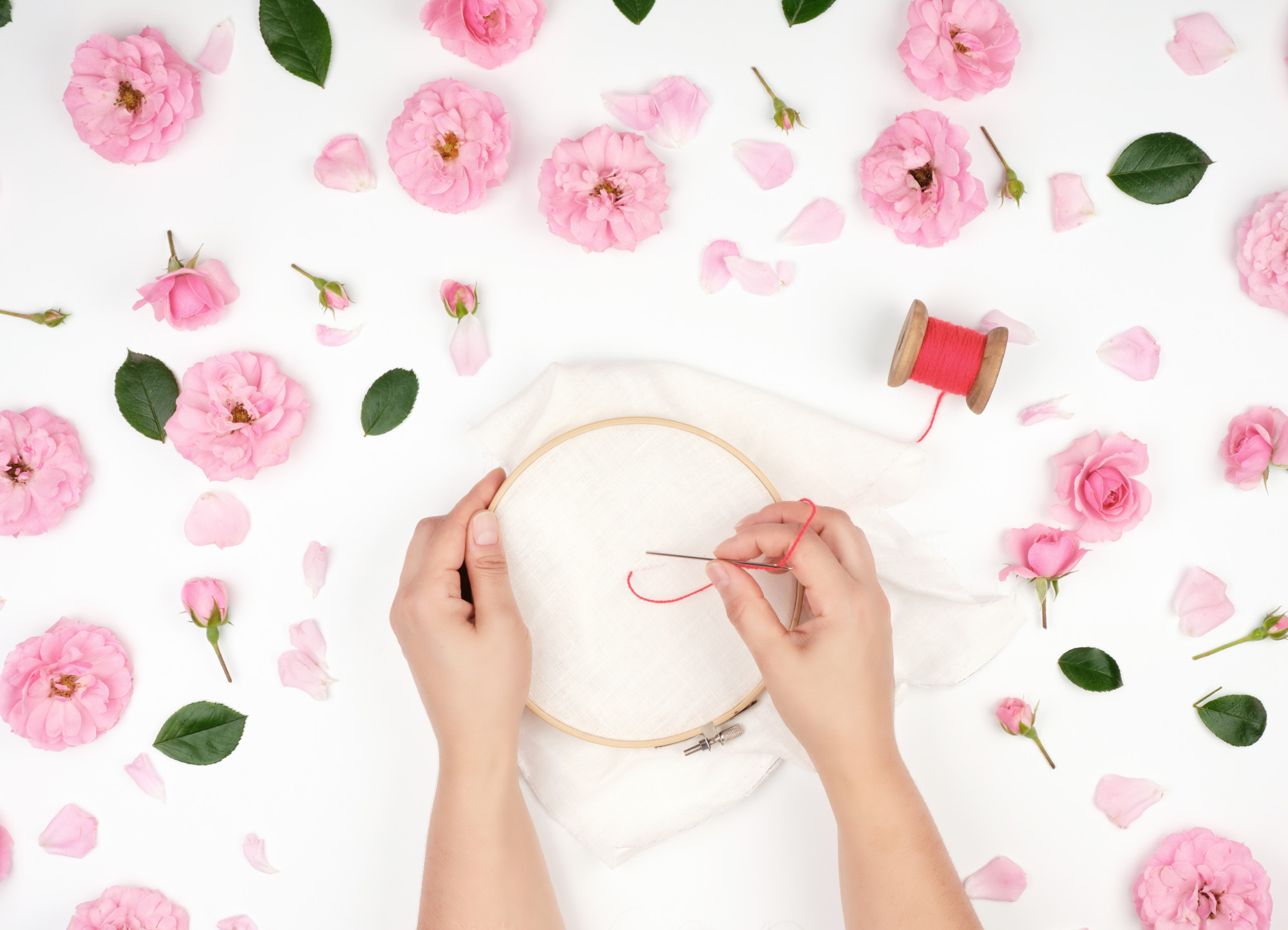 Mano che ricama una rosa su lino naturale